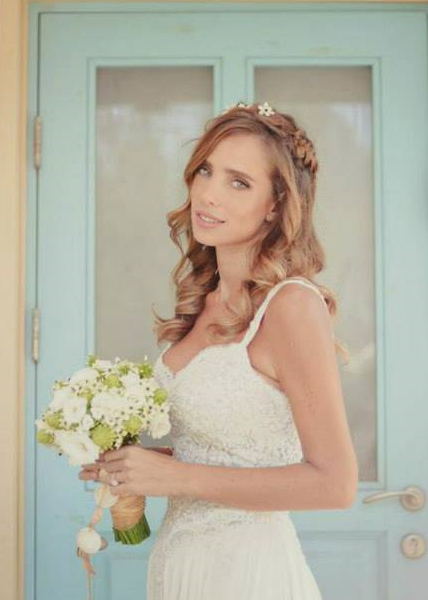 שרי גבעתי ככלה עם זר פרחים וסרט שיער, איפור עדין מול דלת טורקיז